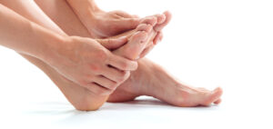 Why do we get fungal nail infections? A person with bare feet is holding on to their foot with both hands
