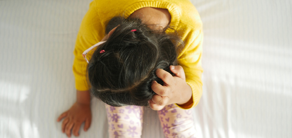 A young child scratching her scalp, possibly due to fungus