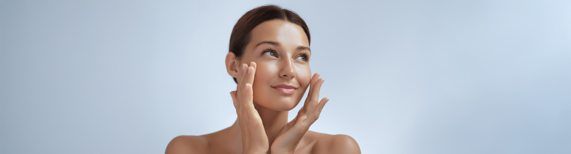 A woman with her hands on her face, applying face cream thinking about urea in moisturisers vs. other ingredients