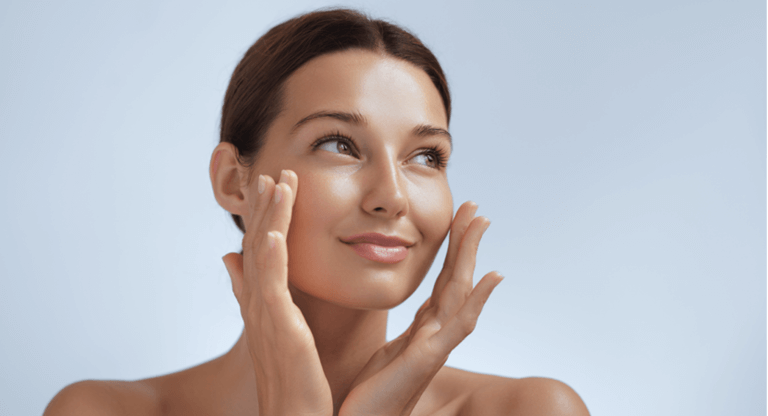 A woman with her hands on her face, applying face cream thinking about urea in moisturisers vs. other ingredients