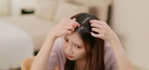 Young woman inspects her scalp in the mirror