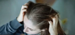 A woman running fingers through her hair wondering why does my hair get oily so fast?