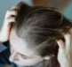 A woman running fingers through her hair wondering why does my hair get oily so fast?